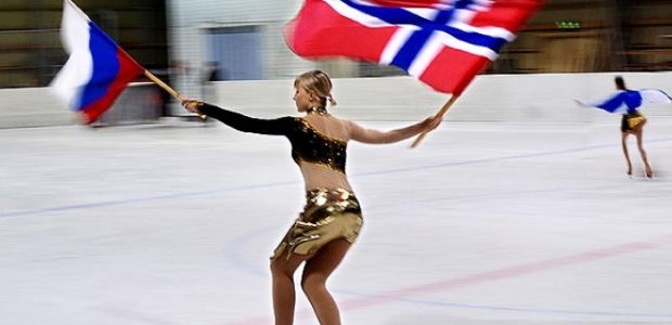 A figure skater holds a Russian and Norweigian flag, taking part in one of the many cross-border sports activities in the Barents Region (Photo Credit: Jonas Karlsbakk/BarentsObserver)