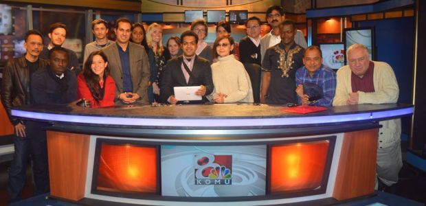 IVLP visitors gather behind the newsdesk at KOMU Television in Columbia, Missouri.