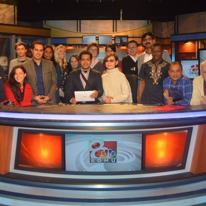 IVLP visitors gather behind the newsdesk at KOMU Television in Columbia, Missouri.