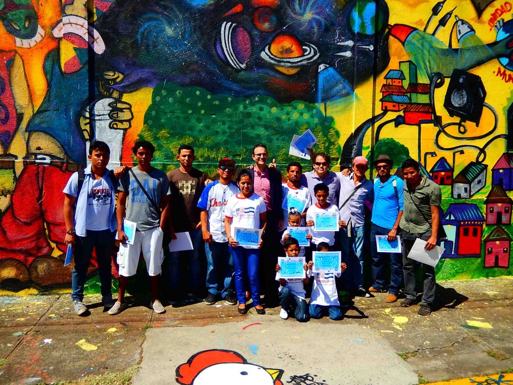 Program participants with their diplomas in front of the completed mural.