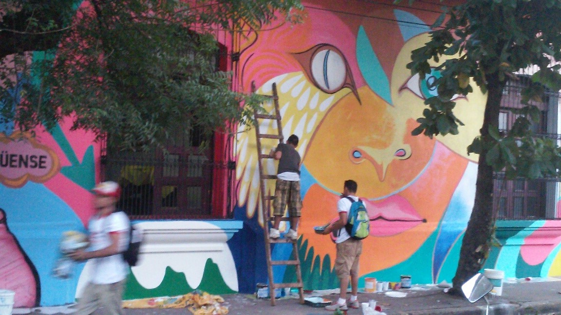 Local youth working on the main feature of the wall, the face of a half-lion, half-woman. 